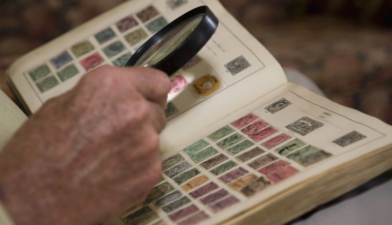 photo d'un philatéliste qui regarde ses timbres avec une loupe